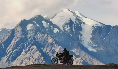 A motorcycle on a ridge in front of a snow-capped peak