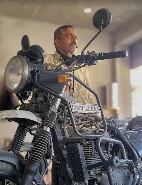A Ladakhi mechanic standing behind a Royal Enfield in his workshop