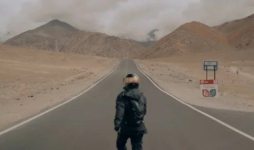 A rider standing on an empty desert road in Ladakh