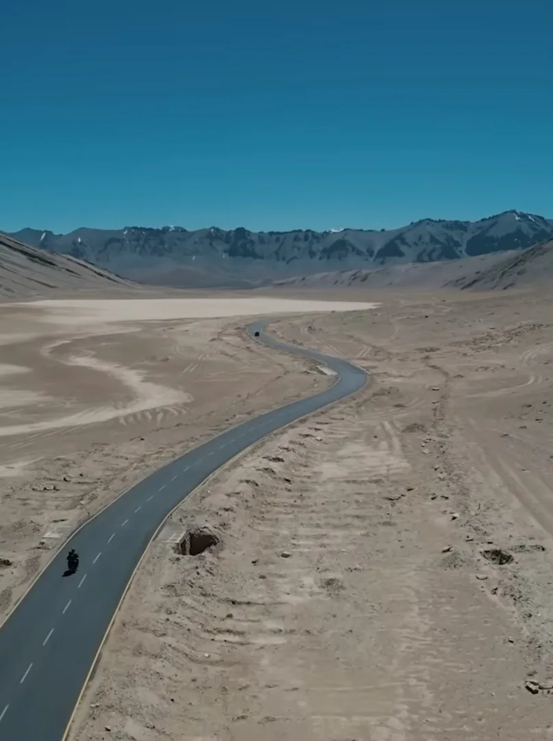 Drone shot of a lone rider on a road crossing the Ladakh desert